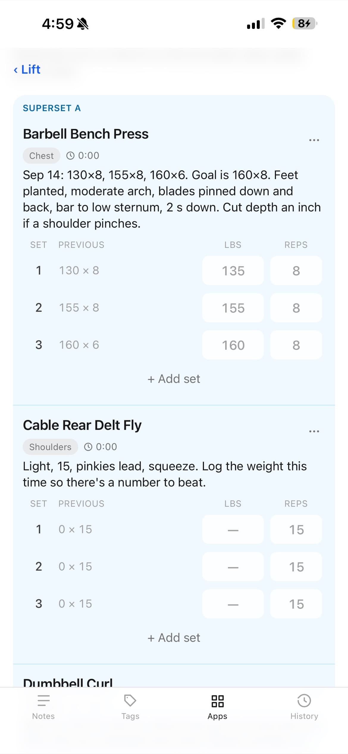 A workout in progress on a phone: Superset A with Barbell Bench Press and Cable Rear Delt Fly, last session's numbers in gray beside the weight and reps to enter, and a coaching note under each exercise.